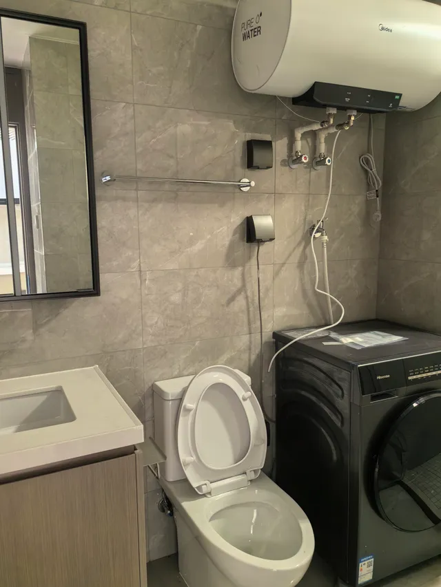 Dorm bathroom with a shower, sink, toilet, and washing machine