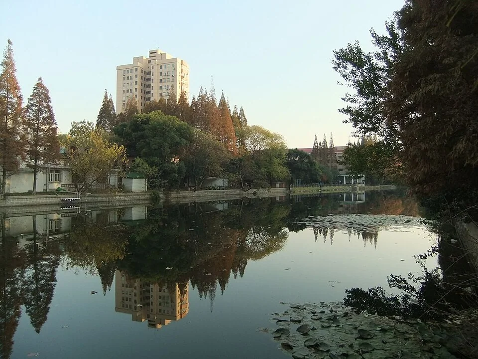 Trees and campus buildings reflected in the Liwa River at ECNU’s Putuo campus
