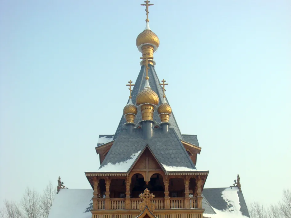 The wooden Saint Nicholas Cathedral replica glowing in the snow at Volga Manor, Harbin